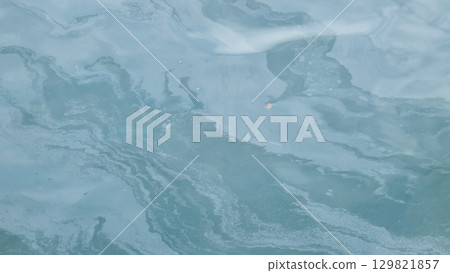 Thin layer of oil polluting ocean water, creating a colorful film on the surface and causing environmental damage 129821857