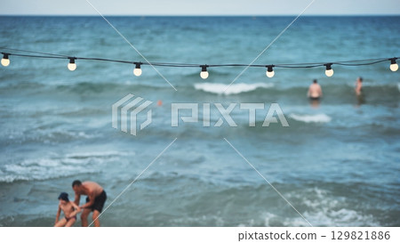 Father and son playing on the beach with string lights and swimmers in Crimea Father and son playing on the beach with string lights and swimmers in Crimea 129821886
