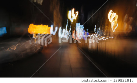 Light trails dancing across urban nightscape, blending motion and city glow through evening pedestrian perspective 129821913