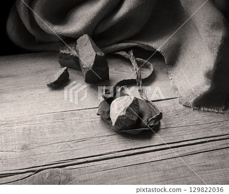 An antique leather sling lies on wooden desk An antique leather sling lies on wooden desk 129822036