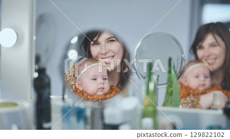 Mother bonding with infant daughter, sharing mirror moment during morning routine 129822102