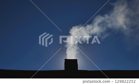 White smoke is coming out from chimney against blue sky, representing pollution or winter heating White smoke is coming out from chimney against blue sky, representing pollution or winter heating 129822252