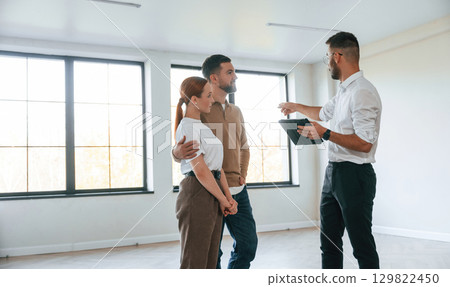 Brand new apartment. Realtor shows a room to a young couple 129822450