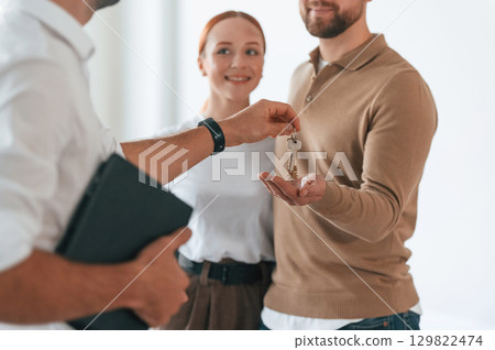 Customers bought the place, receiving the keys. Realtor shows an apartment to a young couple 129822474