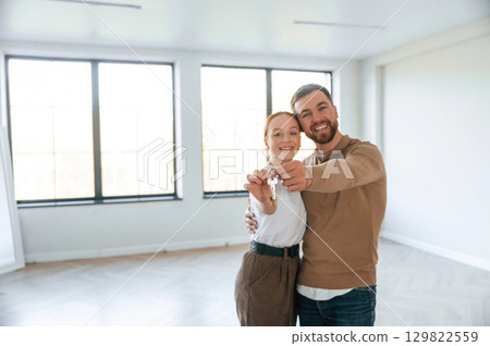 Happy couple as new owners of the house holding the keys in hands 129822559