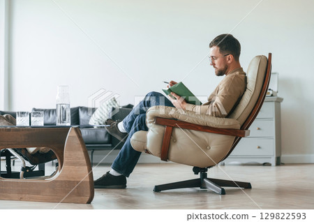 Male psychologist is sitting in the chair with notepad in the office 129822593