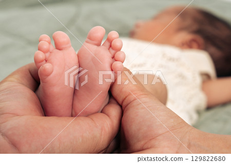 Tiny newborn feet are tenderly cradled in a parent's hands symbolizing love, care, and family bonding. This intimate moment captures the essence of parenthood and the miracle of new life Tiny newborn feet are tenderly cradled in a parent's hands symbolizing love, care, and family bonding. This intimate moment captures the essence of parenthood and the miracle of new life 129822680