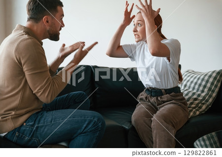 Side view of couple that are arguing. Sitting on sofa 129822861