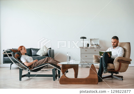 Side view. Woman is sitting in chair at an appointment with a psychologist Side view. Woman is sitting in chair at an appointment with a psychologist 129822877