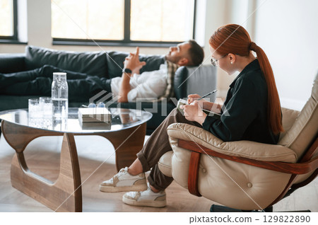 Lying down on the sofa. Man is on the therapy session with female psychologist 129822890