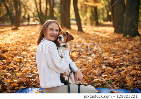 Embracing the animal. Woman is with her cute dog in the autumn forest 129823221