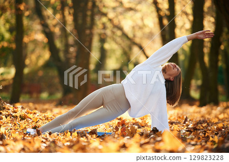 Young beautiful woman is doing yoga in the autumn park 129823228