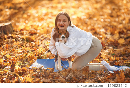 Embracing the animal. Woman is with her cute dog in the autumn forest Embracing the animal. Woman is with her cute dog in the autumn forest 129823242