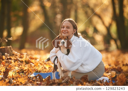 Embracing the animal. Woman is with her cute dog in the autumn forest Embracing the animal. Woman is with her cute dog in the autumn forest 129823243
