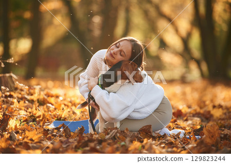 Woman is with her cute dog in the autumn forest Woman is with her cute dog in the autumn forest 129823244