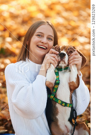 Covering eyes with paws. Woman is with her cute dog in the autumn forest 129823269