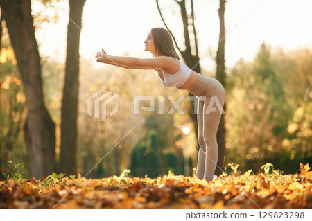 Fitness warm up exercises. Young beautiful woman is doing yoga in the autumn park 129823298