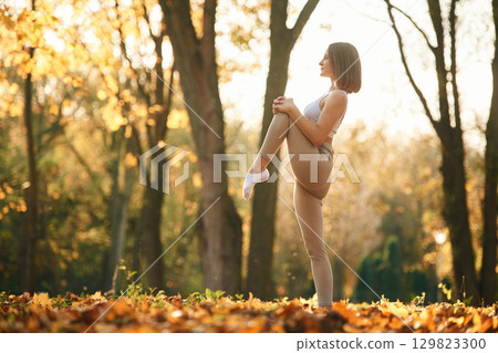 Full height photo. Young beautiful woman is doing yoga in the autumn park 129823300