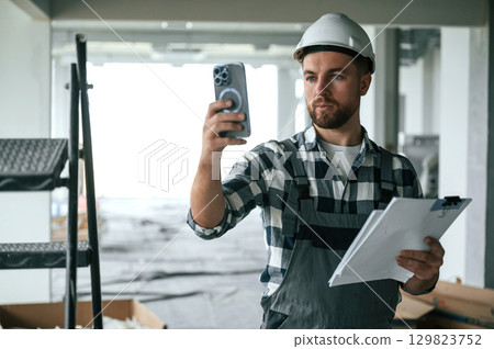 Construction worker in uniform in empty unfinished room 129823752