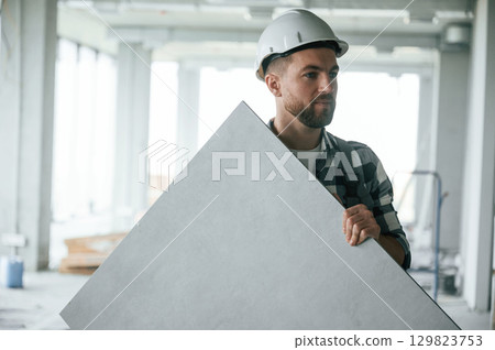 Construction worker in uniform in empty unfinished room 129823753