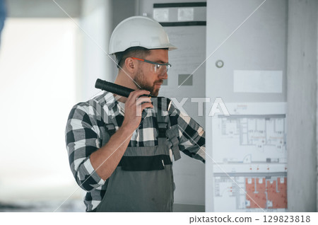Repairman in uniform is in the unfinished building Repairman in uniform is in the unfinished building 129823818