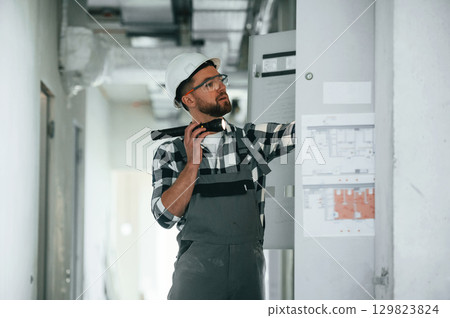 Repairman in uniform is in the unfinished building 129823824