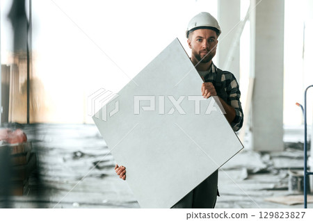 Repairman in uniform is in the unfinished building 129823827