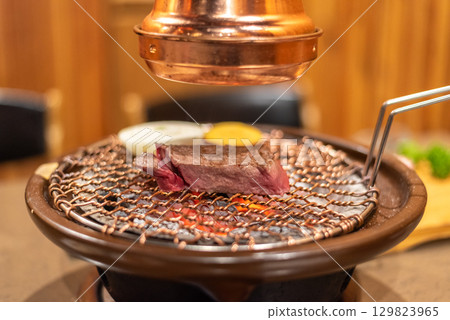 Close-up of a piece of beef steak meat grilling on a traditional Korean barbecue grill 129823965