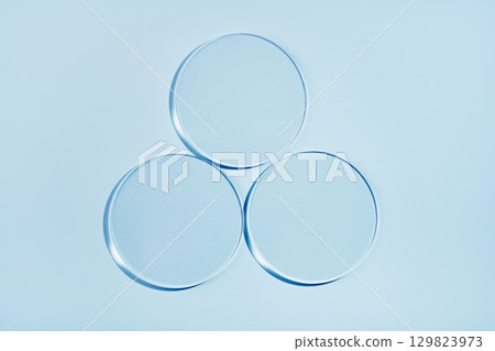 Three empty petri dishes on blue background. Mockup for cosmetic product sample 129823973