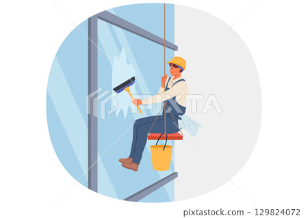 Industrial climber washes windows of skyscraper using brush, hanging at high altitude on rope 129824072