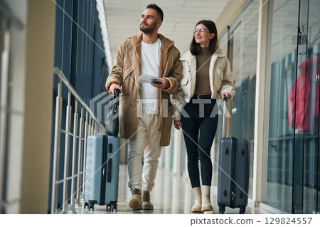 Front view, walking. Couple are in the airport hall together Front view, walking. Couple are in the airport hall together 129824557