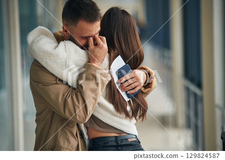 Man is crying, embracing, farewell. Couple are in the airport hall together 129824587