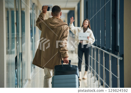 Greetings gesture, arrival of the man. Couple are in the airport hall together Greetings gesture, arrival of the man. Couple are in the airport hall together 129824592