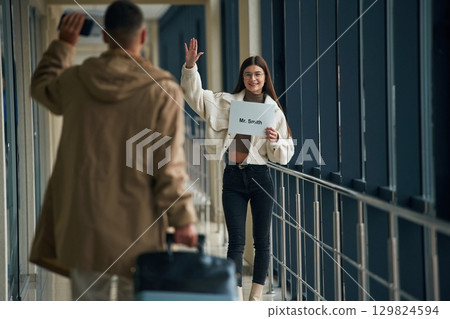Greetings gesture, arrival of the man. Couple are in the airport hall together 129824594