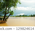 Serene Laos Mekong River Landscape with high brown water, Lush Trees and Cloudy Skies, Don Det 129824614