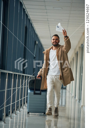 Running, late for flight, with tickets in hand. Young handsome man in the airport Running, late for flight, with tickets in hand. Young handsome man in the airport 129824667