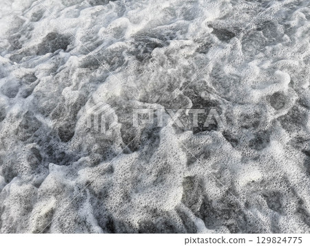 Ocean waves crashing with foam creating a dynamic texture and movement in the water Ocean waves crashing with foam creating a dynamic texture and movement in the water 129824775