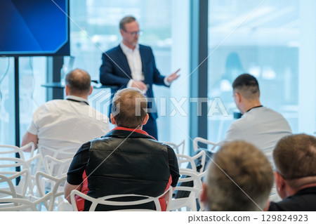 Audience listening to business presentation in modern conference room setting Audience listening to business presentation in modern conference room setting 129824923
