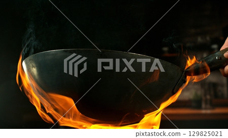 Freeze Motion of Empty Wok Pan with Flames Burning Around. Kitchen Interior on Background. Freeze Motion of Empty Wok Pan with Flames Burning Around. Kitchen Interior on Background. 129825021