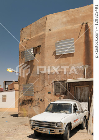 Old White Pickup Truck Parked in Front of Rustic House in Saudi Arabia 129825491