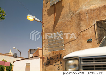 Close-Up of Old White Pickup Truck in Front of Rustic Building, Saudi Arabia 129825495