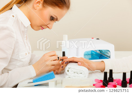 Woman in beauty salon getting manicure done. Woman in beauty salon getting manicure done. 129825751