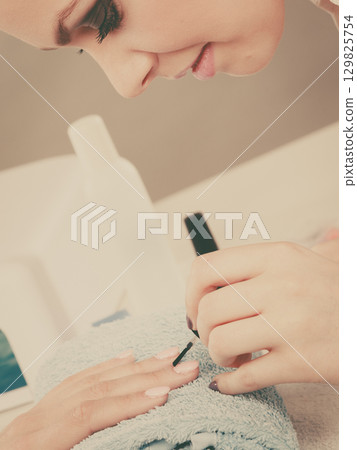 Woman in beauty salon getting manicure done. Woman in beauty salon getting manicure done. 129825754