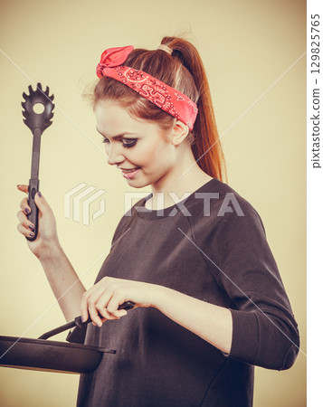 Retro girl cooking and frying on pan. 129825765
