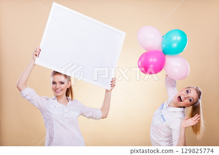 Two girls with blank board and balloons 129825774