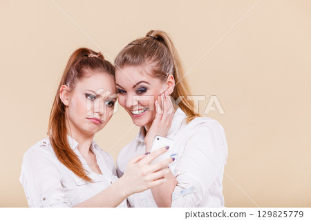 Girls using mobile phone reading message Girls using mobile phone reading message 129825779