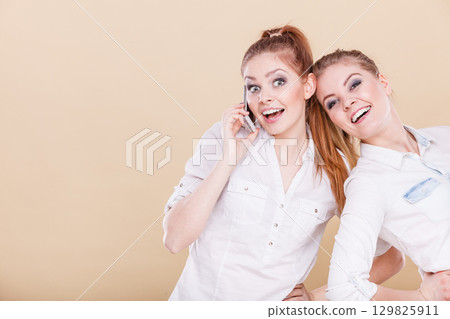 Girls using mobile phone talking 129825911