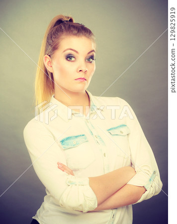Angry woman looking very displeased standing with arms folded Angry woman looking very displeased standing with arms folded 129825919