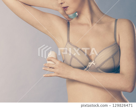 Girl applying stick deodorant in armpit 129826471
