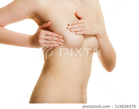 Woman examining her breasts for breast cancer 129826479